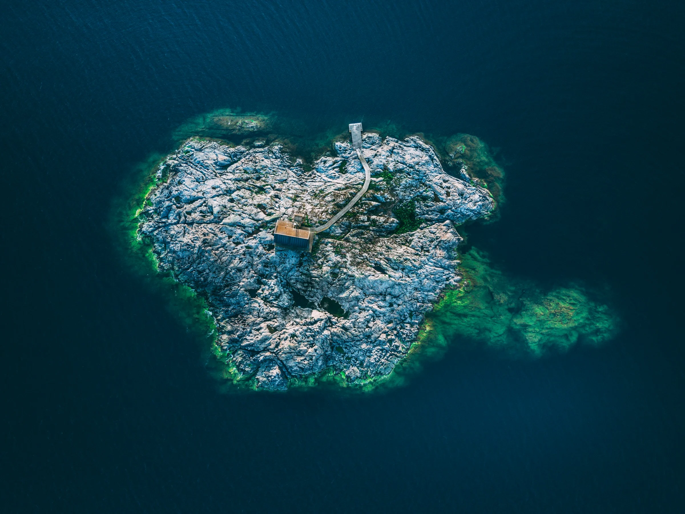 Klippö i skärgården vid Utö sedd ovanifrån, omgiven av mörkt vatten